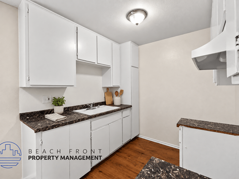 A kitchen with white cabinets and a granite countertop.