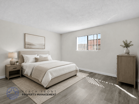 A well-lit bedroom with a large bed and a wooden nightstand.