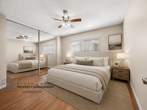 A bedroom with a large bed, a ceiling fan, and a mirrored wall.