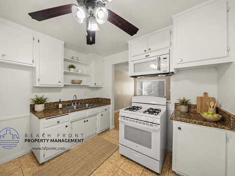 A kitchen with white cabinets and a stove top oven.