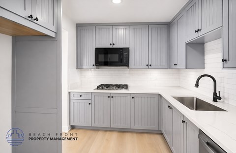 A kitchen with grey cabinets and a white countertop.