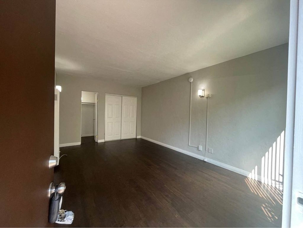 an empty living room with wood floors and white walls