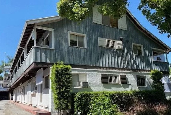 a house with a green facade and bushes