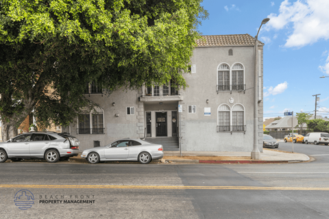 A street view of a building with cars parked in front.