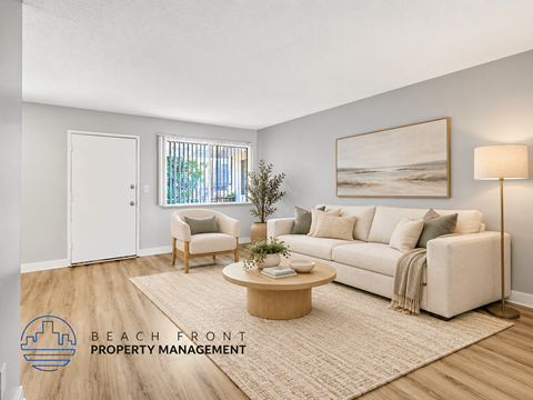 A living room with a white couch, a wooden coffee table, and a painting on the wall.