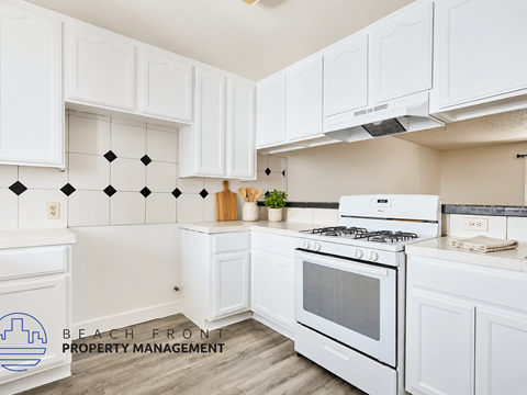 A kitchen with white cabinets and a white stove top oven.