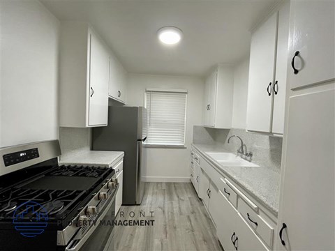 A kitchen with white cabinets and a black stove top oven.
