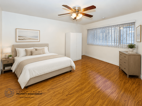 A bedroom with a bed, dresser, and ceiling fan.