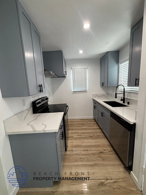 A kitchen with a white counter top and wooden floors.