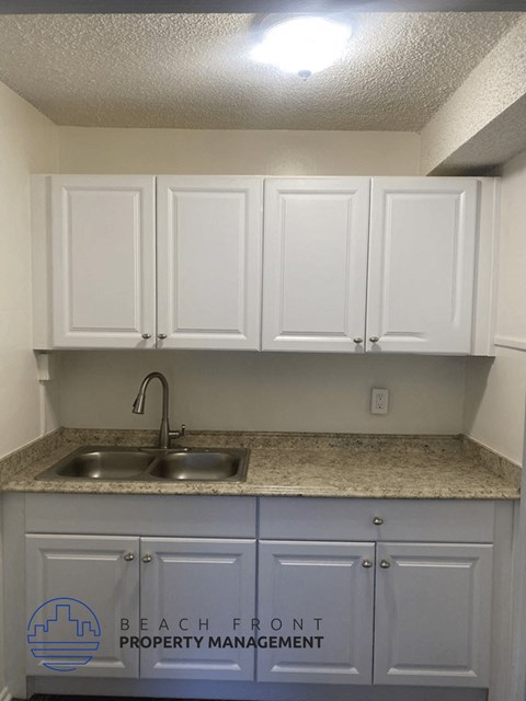 a kitchen with white cabinets and a sink and a counter