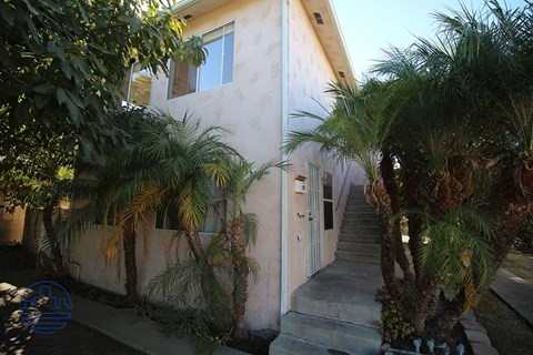 A house with a staircase and trees in front.