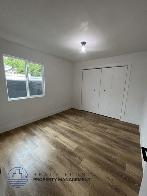 a bedroom with white cabinets and a wood floor
