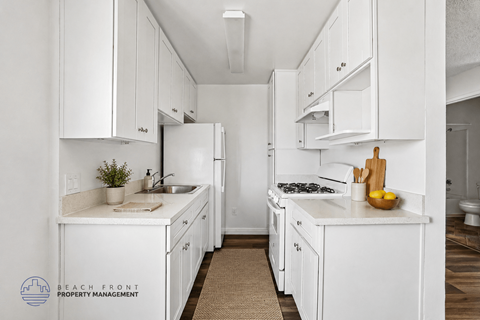 A kitchen with white cabinets and appliances, a sink, and a cutting board with lemons on the counter.