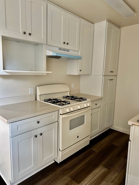 A white kitchen with a stove and cabinets.