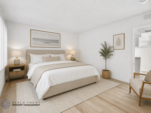 A bedroom with a large bed, a small plant, and a chair.