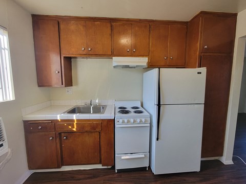 an empty kitchen with white appliances and wooden cabinets