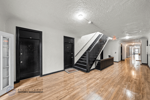 A spacious room with wooden floors and a staircase leading to another level.