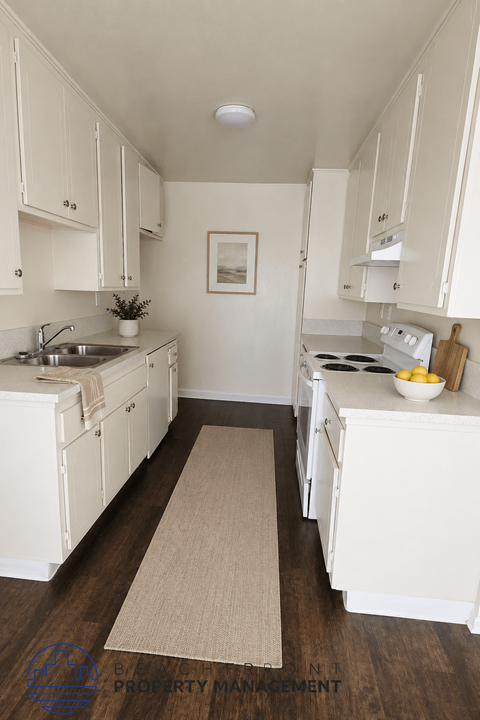 A kitchen with white cabinets and a beige rug on the floor.