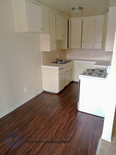 A kitchen with white appliances and wooden floors.