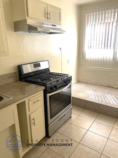 A kitchen with a black stove top oven and a white tile floor.