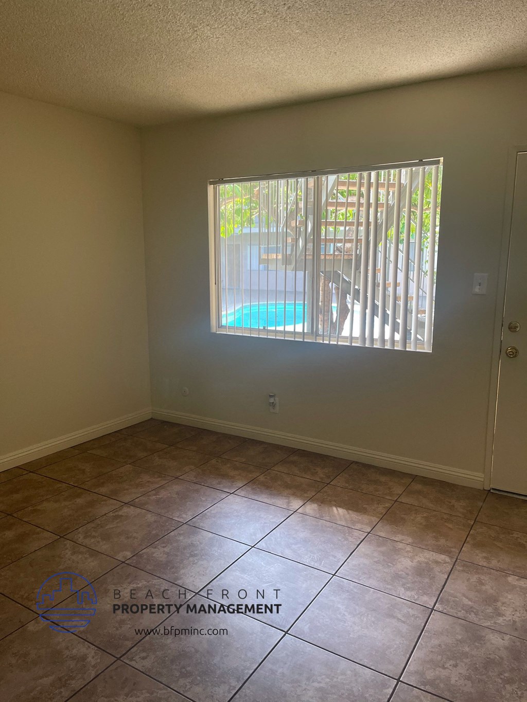an empty living room with a window overlooking a swimming pool