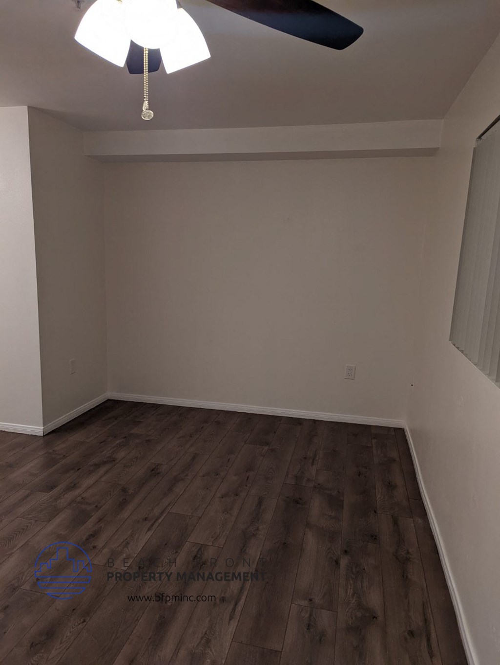 a empty room with wooden floors and a ceiling fan