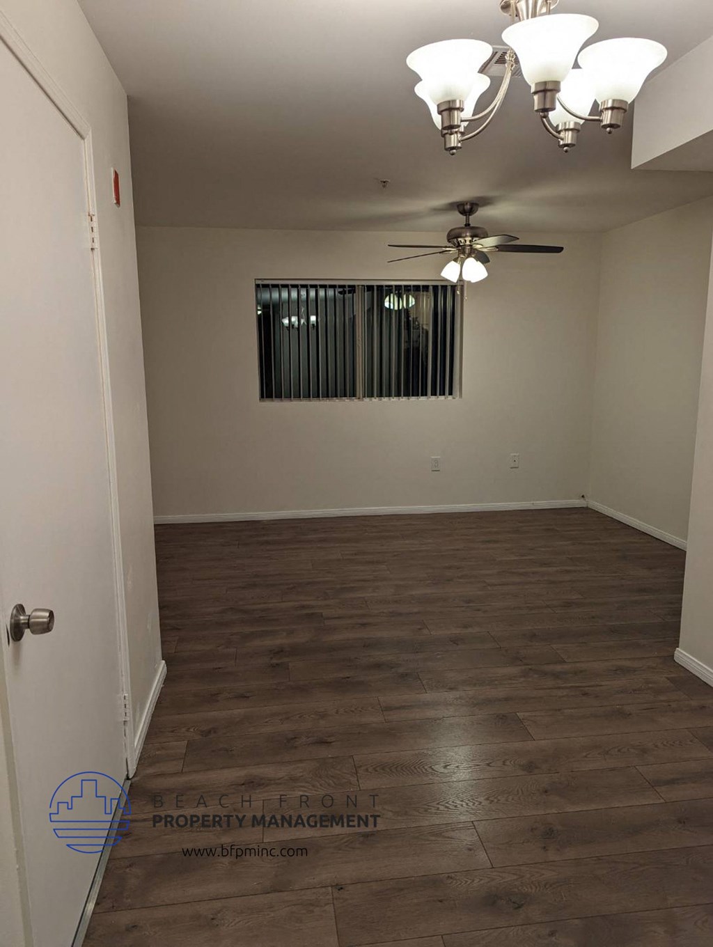 an empty living room with wood flooring and a ceiling fan