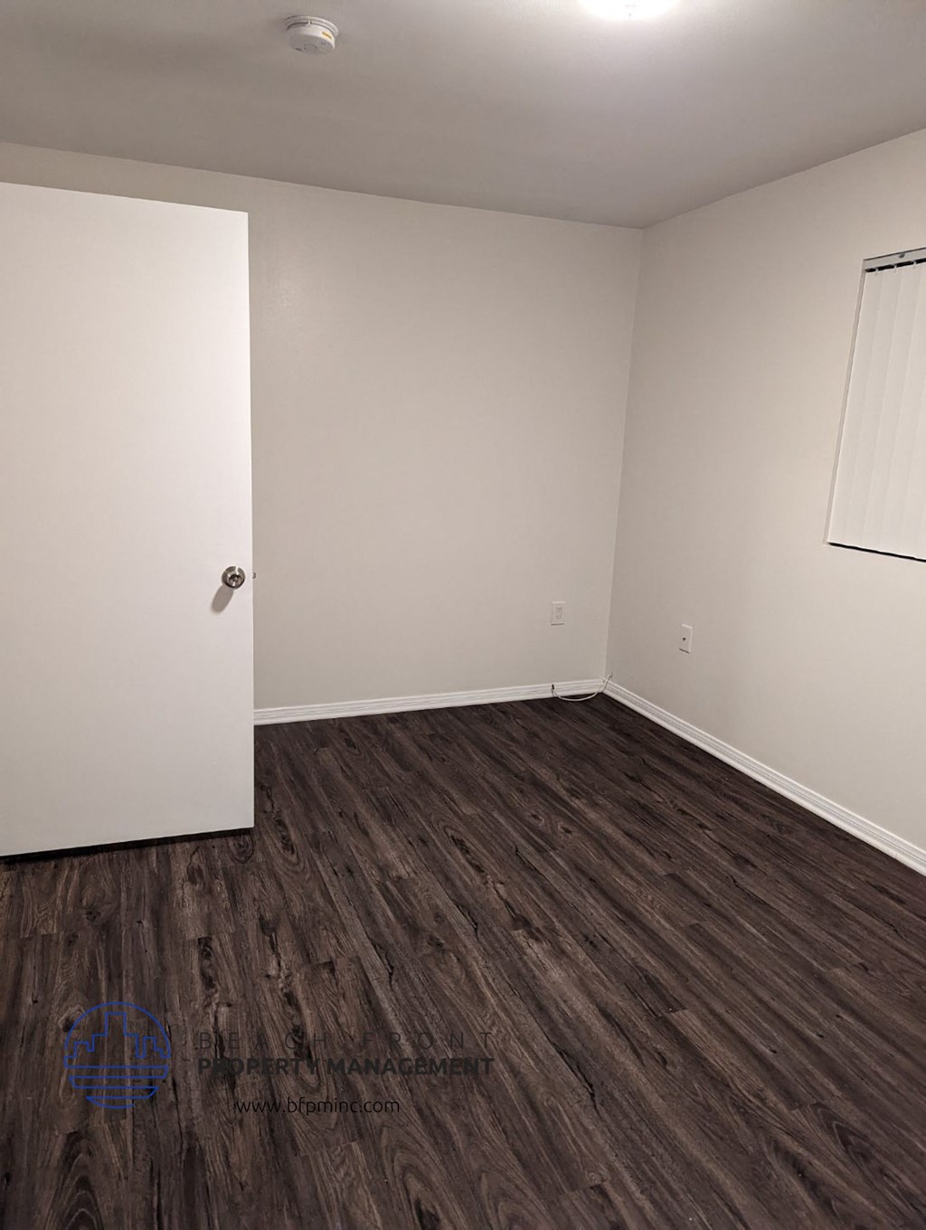an empty room with wooden floors and a white door