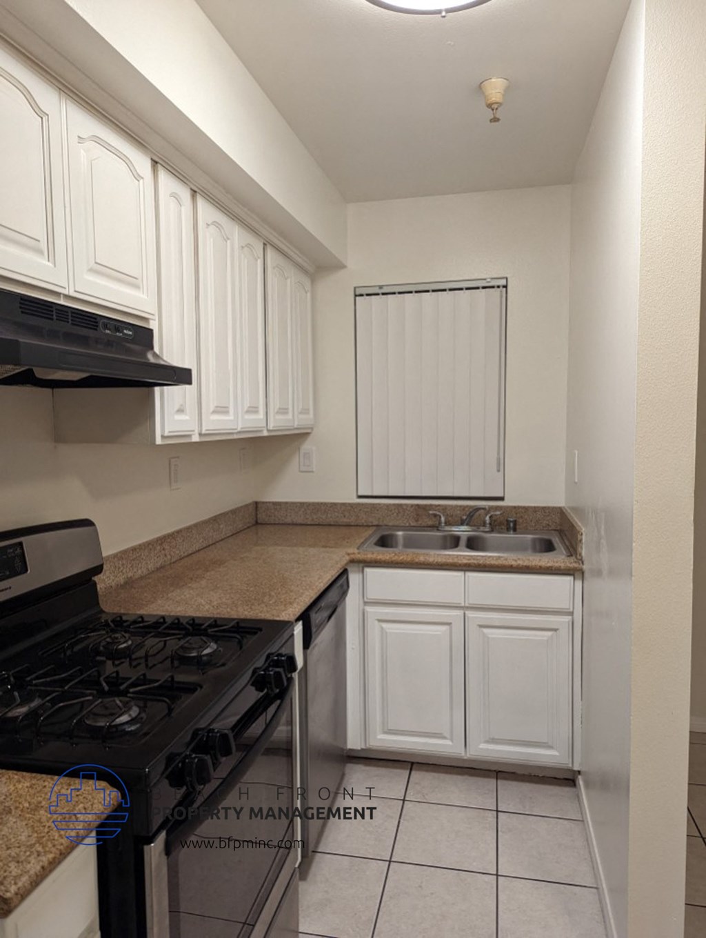 a kitchen with white cabinets and a sink and a stove