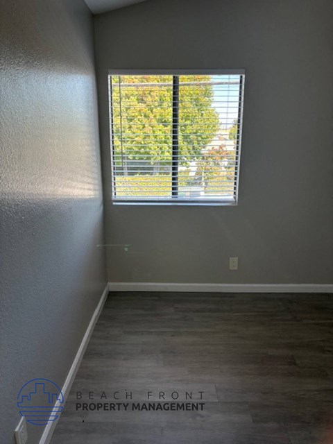 an empty room with a window and a wooden floor