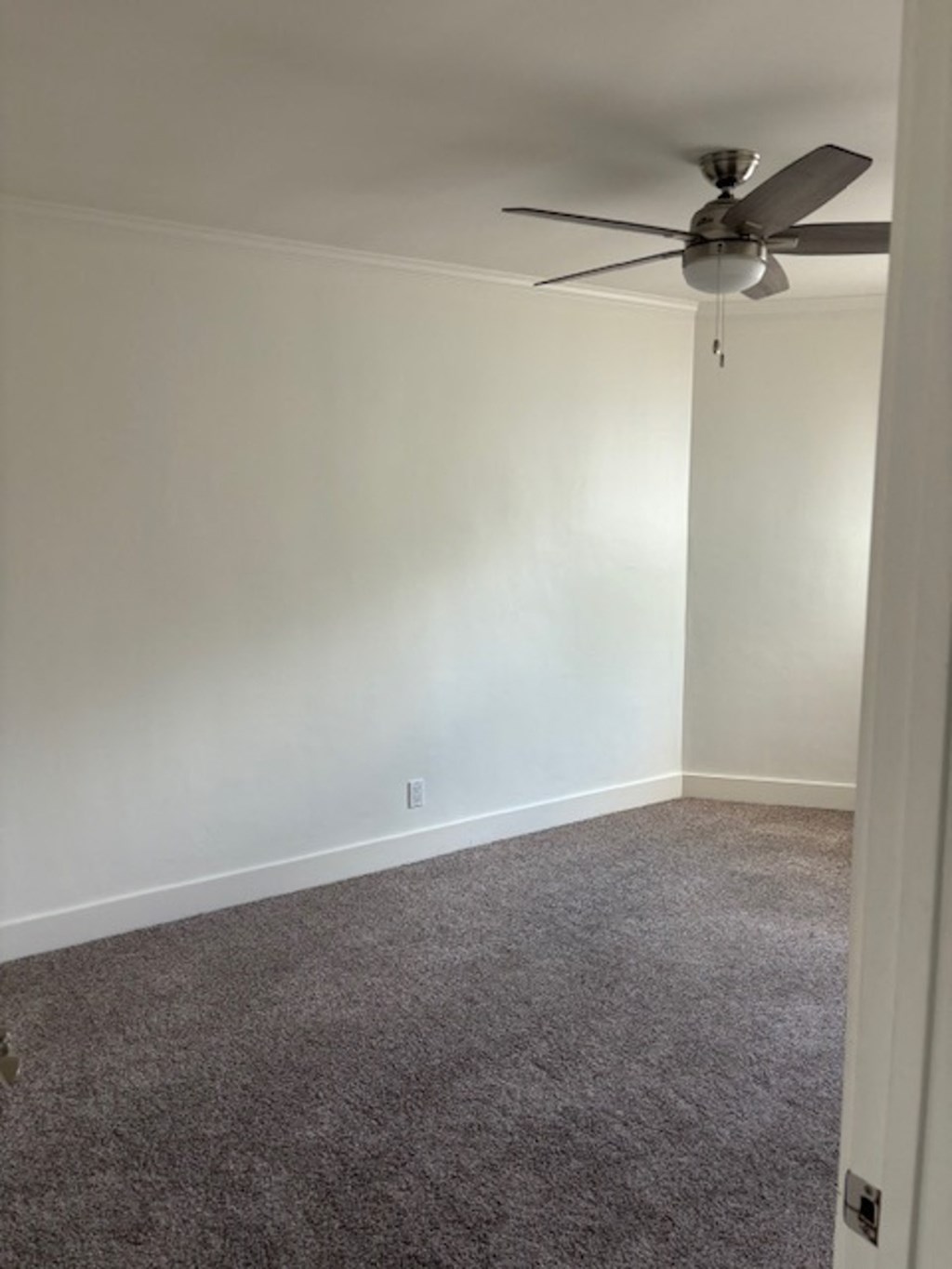 a room with white walls and a ceiling fan