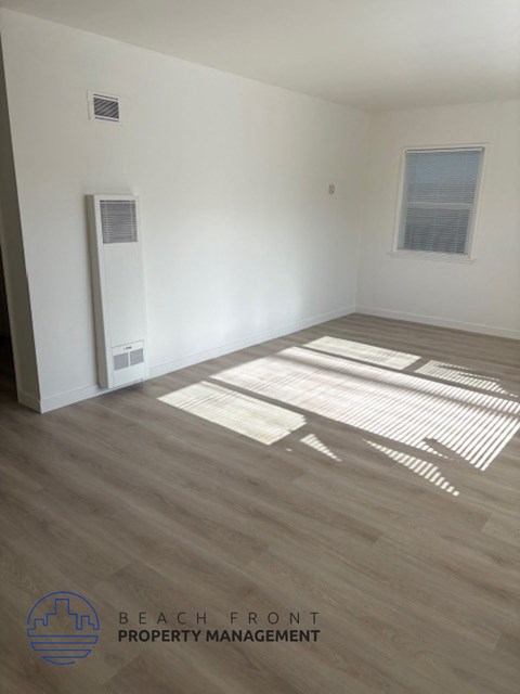 A room with wooden flooring and a window letting in sunlight.