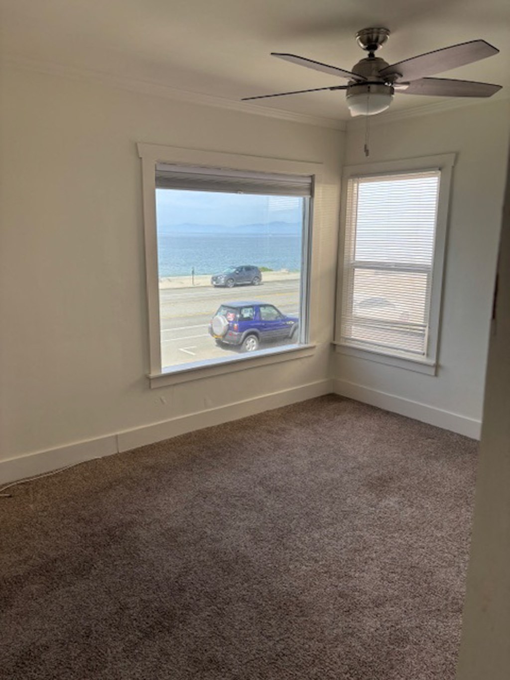 a room with a view of the beach and a ceiling fan