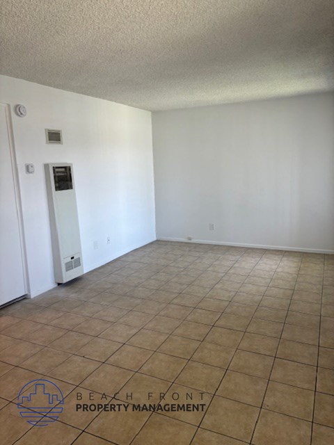 an empty living room with a tile floor and white walls