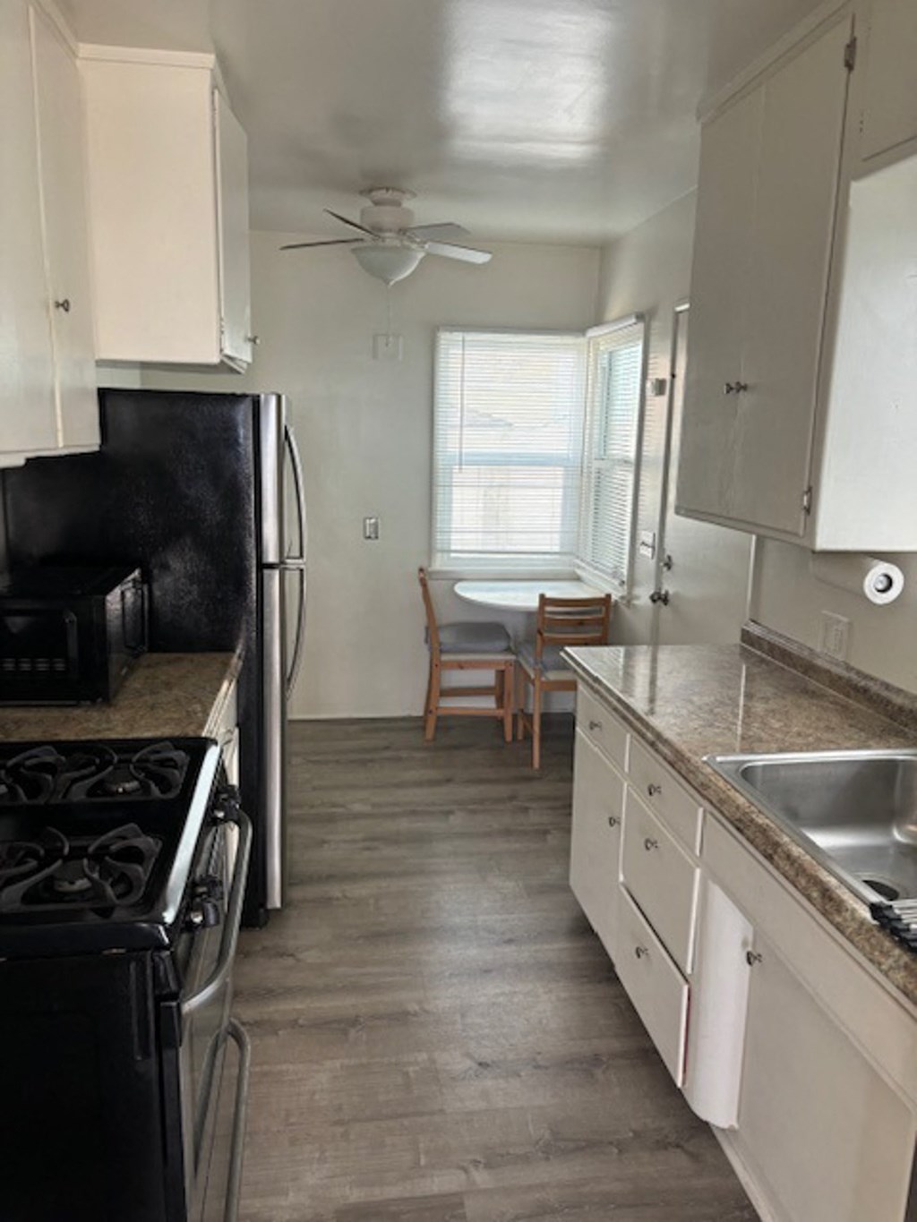 a kitchen with white cabinets and black appliances and a table