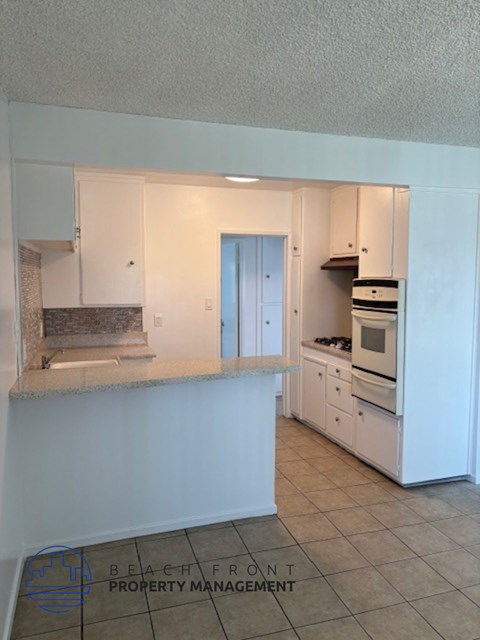 an empty kitchen with white cabinets and a counter top