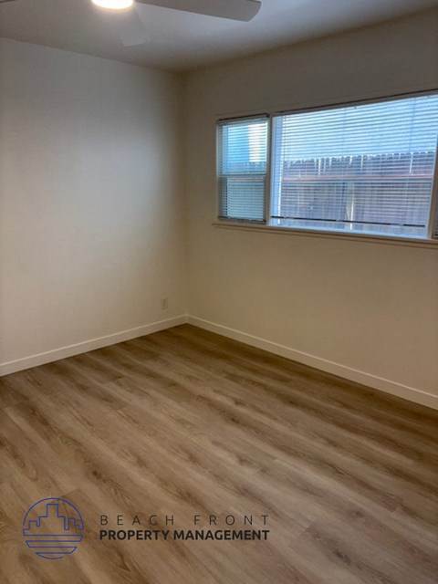 A room with wooden flooring and a window with blinds.