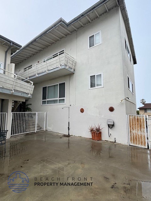 A white two-story house with a balcony on the second floor.