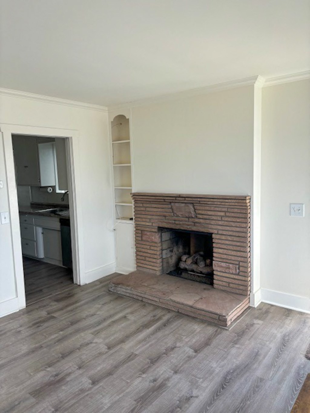 a living room with a brick fireplace and a wooden floor