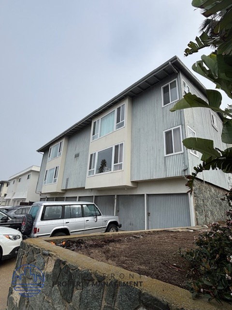 A grey building with a white car parked in front.
