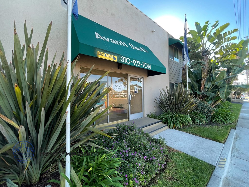 the front of an apartment building with a green awning and plants