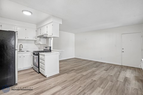 A kitchen with white cabinets and a black refrigerator.