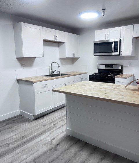 A kitchen with white cabinets and a wooden counter.