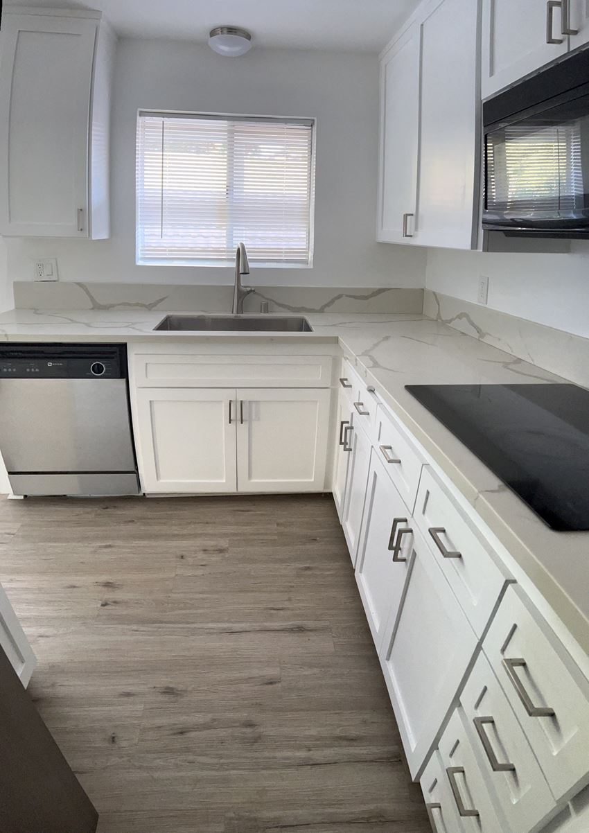 an empty kitchen with white cabinets and white counter tops and a sink