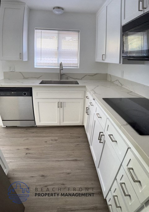 a white kitchen with white cabinets and white counter tops and a sink