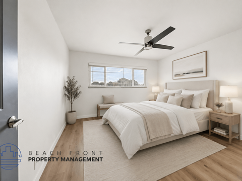 A well-lit bedroom with a large bed and a ceiling fan.
