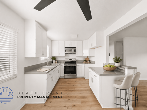 A modern kitchen with white cabinets and a wooden floor.