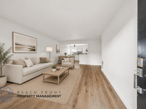A spacious living room with a white couch, wooden coffee table, and a painting on the wall.