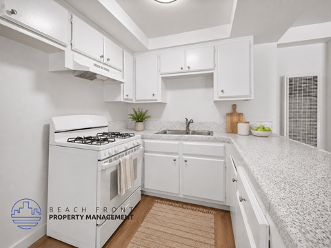 A kitchen with white cabinets and a white stove top oven.