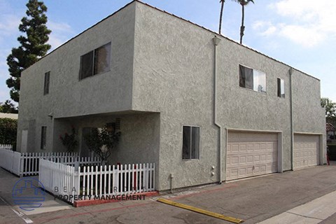a gray house with a white fence and a garage door
